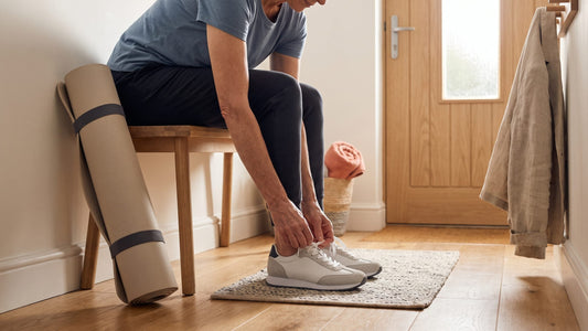 Person lacing up trainers by a front door in soft morning light
