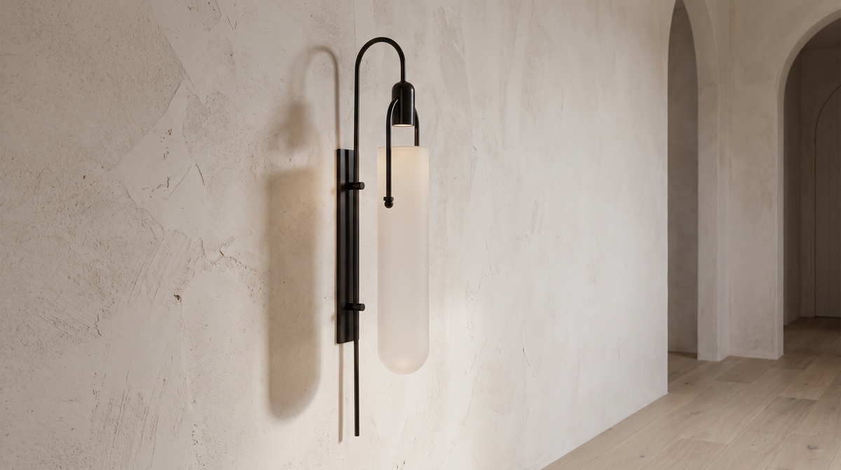 Sora wall light with a black gooseneck arm and frosted glass capsule shade on a limewashed plaster wall